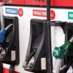 Gas pump panel with three nozzle handles (red, blue, green) at a fuel station, labeled Pertamax and Pertamina Dex.