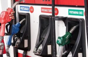 Gas pump panel with three nozzle handles (red, blue, green) at a fuel station, labeled Pertamax and Pertamina Dex.