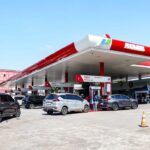 Busy Pertamina gas station with several cars refueling under a red-and-white canopy.