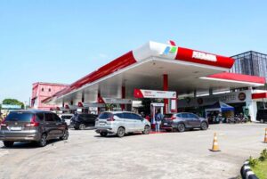 Busy Pertamina gas station with several cars refueling under a red-and-white canopy.
