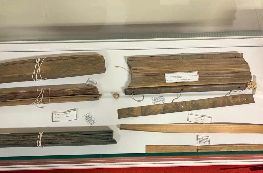 Display case containing bundled parchment scrolls tied with string and several wooden rulers with labels, as a museum exhibit item.