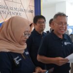 Group of professionals in navy shirts gathered indoors near a wall with 'Engineering Research and Innovation Center' signage behind them.