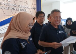 Group of professionals in navy shirts gathered indoors near a wall with 'Engineering Research and Innovation Center' signage behind them.