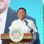 Man delivering a speech at a podium with the Indonesian national emblem seal visible on the lectern