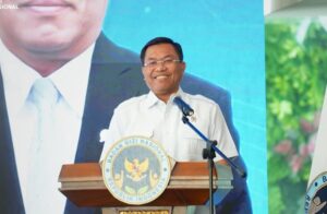 Man delivering a speech at a podium with the Indonesian national emblem seal visible on the lectern