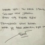 Handwritten note on white paper with a signature at the bottom; faint circular doodle on the left edge.