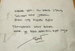Handwritten note on white paper with a signature at the bottom; faint circular doodle on the left edge.