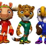 Three cartoon animal mascots in soccer uniforms: a red-moose with a ball, a green-leopard, and a blue-eagle stand together.