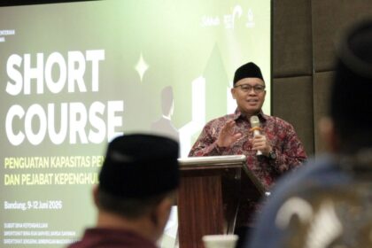 Man in batik shirt and black cap speaks at a podium during a seminar, with a large 'SHORT COURSE' banner behind.