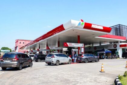 Busy Pertamina gas station with several cars refueling under a red-and-white canopy.