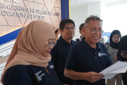 Group of professionals in navy shirts gathered indoors near a wall with 'Engineering Research and Innovation Center' signage behind them.