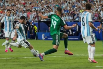 Soccer players from Argentina (blue-and-white stripes) and a green-clad opponent contest the ball on a crowded field during a match.