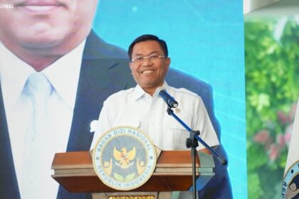 Man delivering a speech at a podium with the Indonesian national emblem seal visible on the lectern