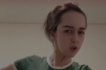 Close-up of a person wearing a green shirt with a white collar, looking at the camera indoors.